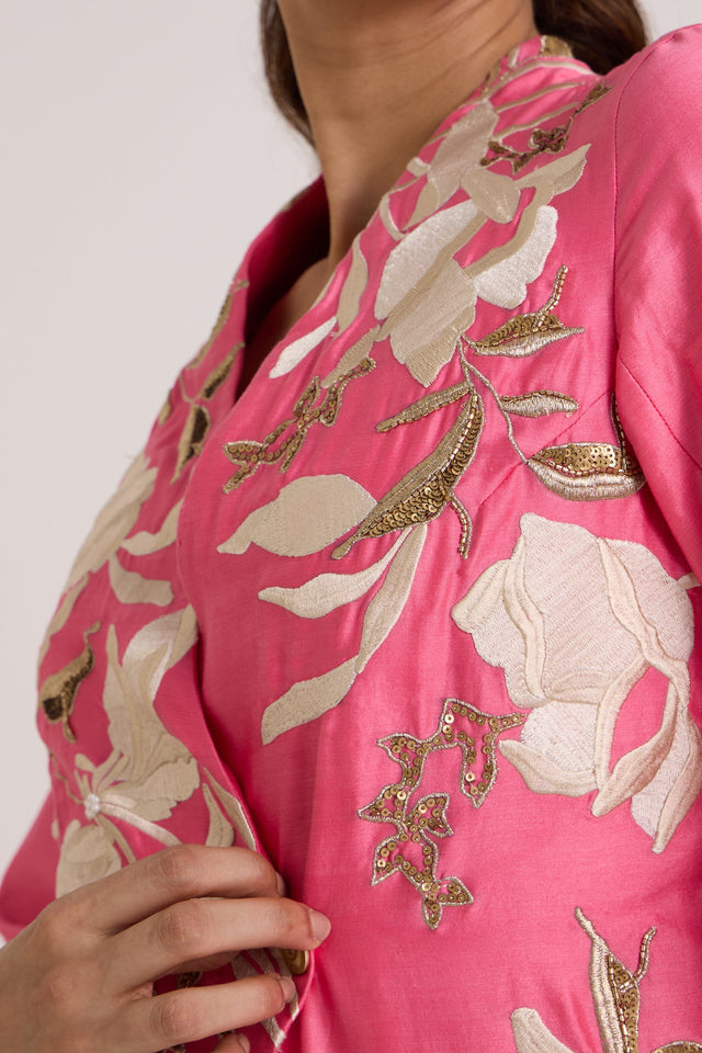 Close-up of the Eddie pink wrap top notched neckline with ivory and gold floral applique