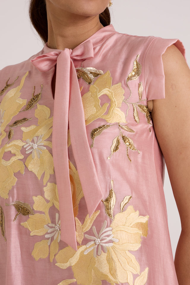 Close-up of the Helga ice pink neck bow, tab sleeve and yellow floral applique