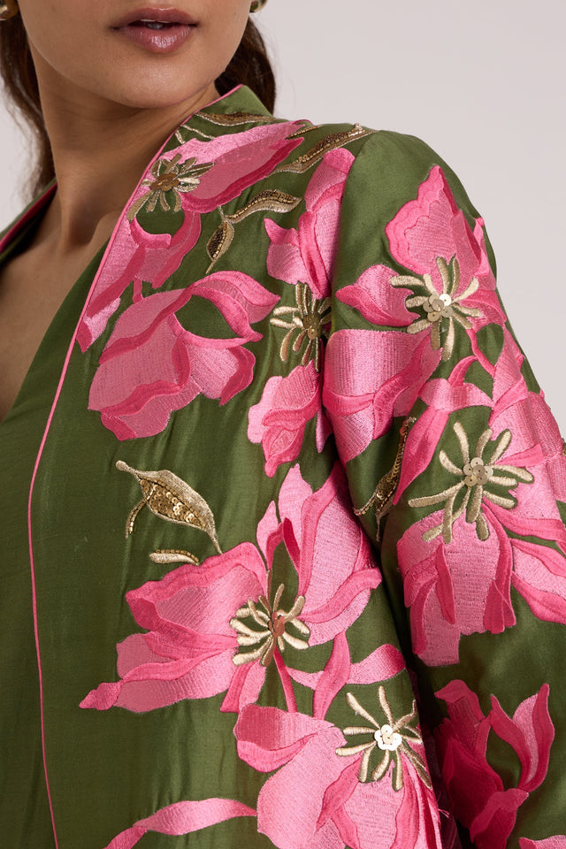 Close-up of the Rafiya jacket front edge with pink lilies, gold details and the V neck dress