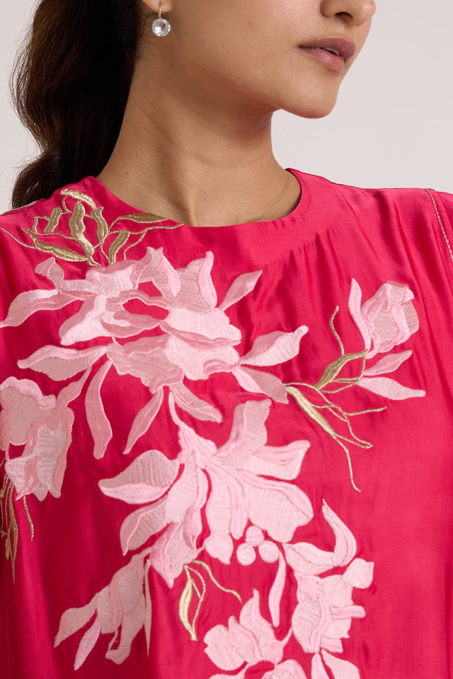 Close-up of the Zuma pink top round neckline and pale pink floral applique