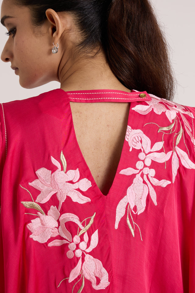 Close-up of the Zuma pink top V back opening with pale pink floral applique