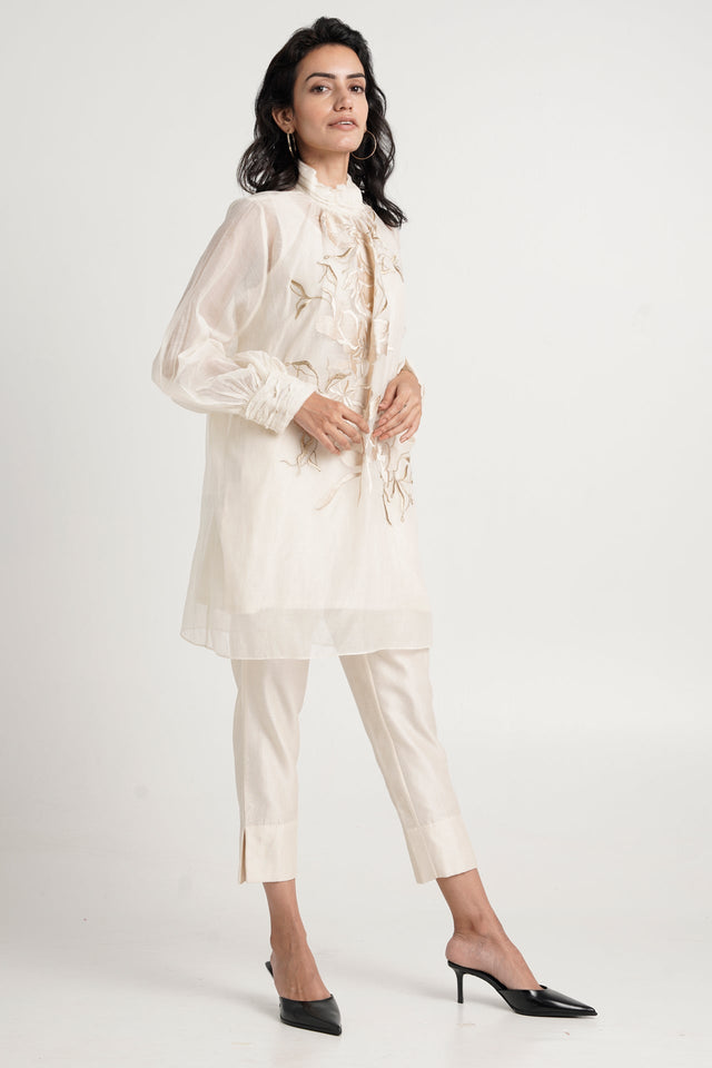 Alba ivory tunic set with high ruffled neck and black heels, three quarter view