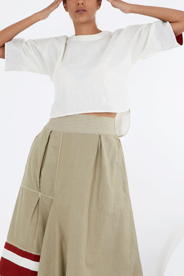 Ivory relaxed crop top with arms raised over khaki pants with red stripe hem, front view