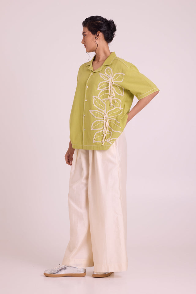 Binda green short sleeve shirt with white leaf embroidery over ivory wide pants, side view
