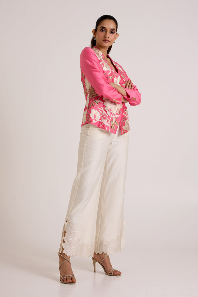 Jay pink Eddie wrap top with arms crossed and ivory pants, three quarter view