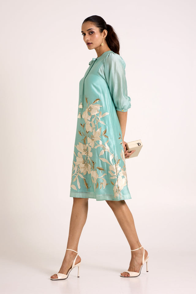 Aqua Vinny day dress walking with a clutch, side view of the ivory floral hem