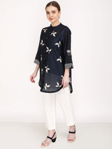 Model wearing the navy leaf print shirt with embroidered striped cuffs and ivory pants, angled view