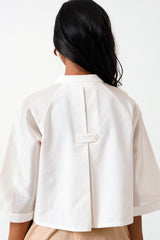 Close back view of the Ivory Zola crop shirt with button tab and raglan sleeves