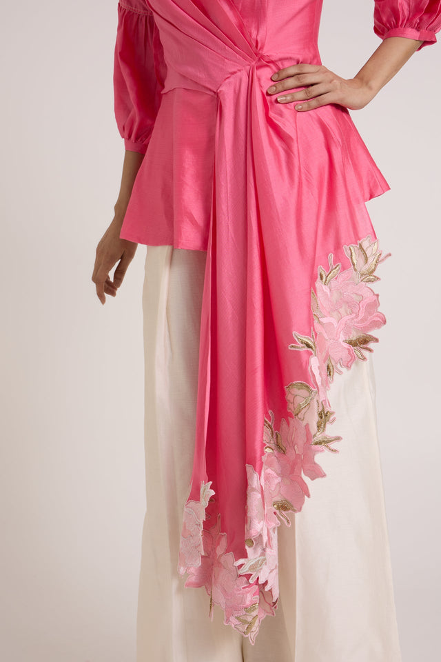 Close view of the Velan top cascading drape with floral applique over ivory pants