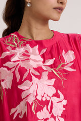Close-up of the Zuma pink top round neckline and pale pink floral applique