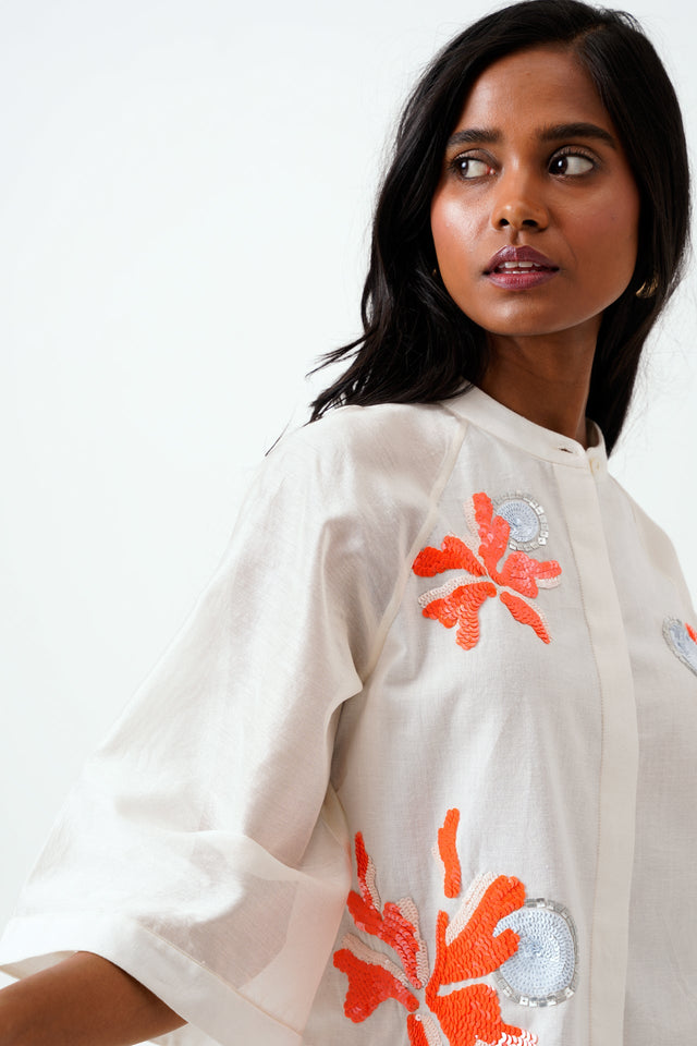 Close view of the Ivory Zola raglan sleeve and orange and silver floral appliques