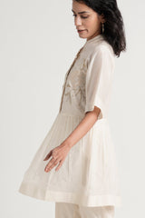 Ivory Abe 2.5 tunic in motion, side view of the flared peplum and embroidered front