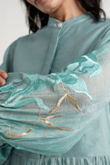 Close-up of the Aqua Abe 2.0 sheer sleeve with aqua and gold floral embroidery
