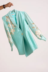 Aqua Alfie blazer top without the belt on a hanger, side view of the wrap front and button