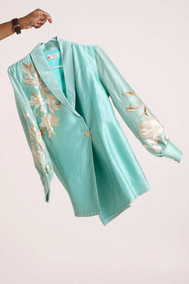 Aqua Alfie blazer top without the belt on a hanger, side view of the wrap front and button