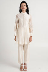 Ivory Abe 2.0 peplum tunic and slim pants with white heels, full length front view