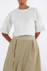 Ivory crop top with round neck and wide elbow sleeves over khaki wide pants, close front view