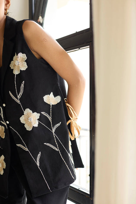 Close-up of the Black Denim Floral Jacket white flower embroidery and tan side tie