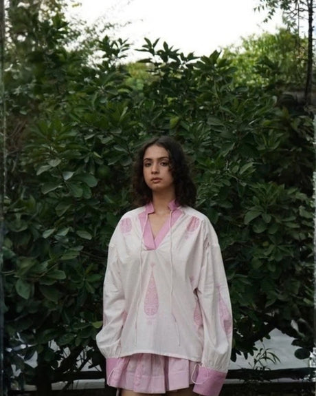 Model wearing the Bella Top by MAGO in white with pink block print, V-neck and pink cuffs, front view