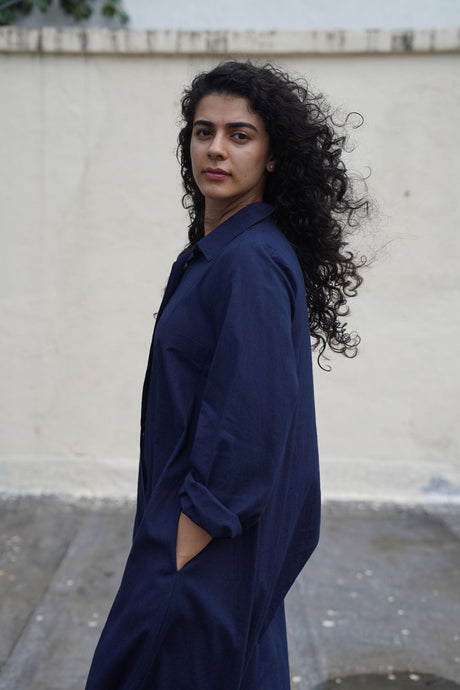 Model turning in the navy Suga jumpsuit with rolled sleeves, close angled view