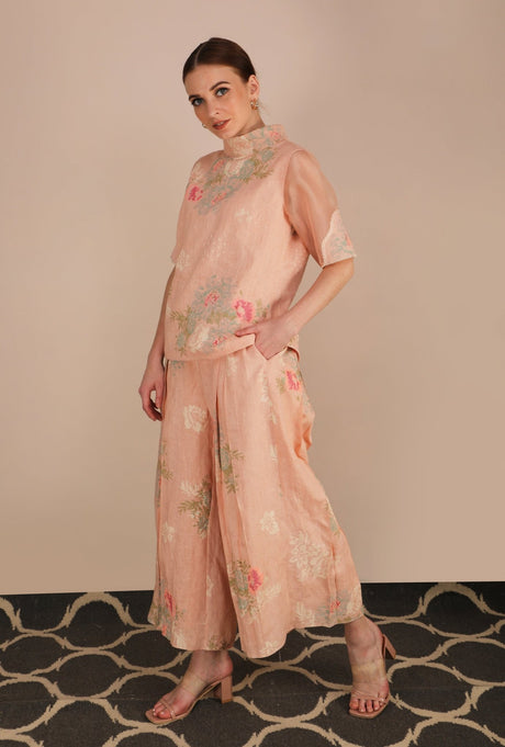 Model posing in the peach rose print culottes with hand in pocket, side angle view