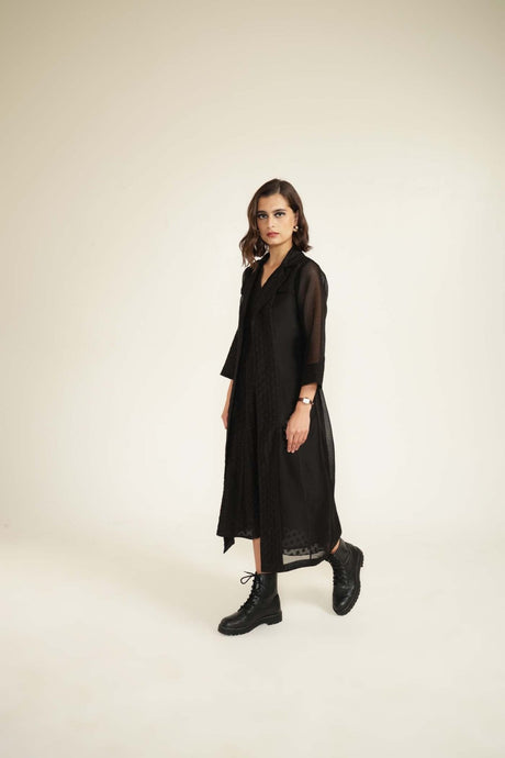 Model walking in the black embroidered organza jacket and dress, three-quarter view