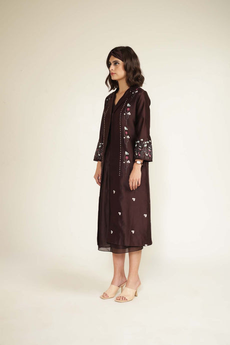Model wearing the grape printed jacket with embroidered bell sleeves over the dress, three-quarter view