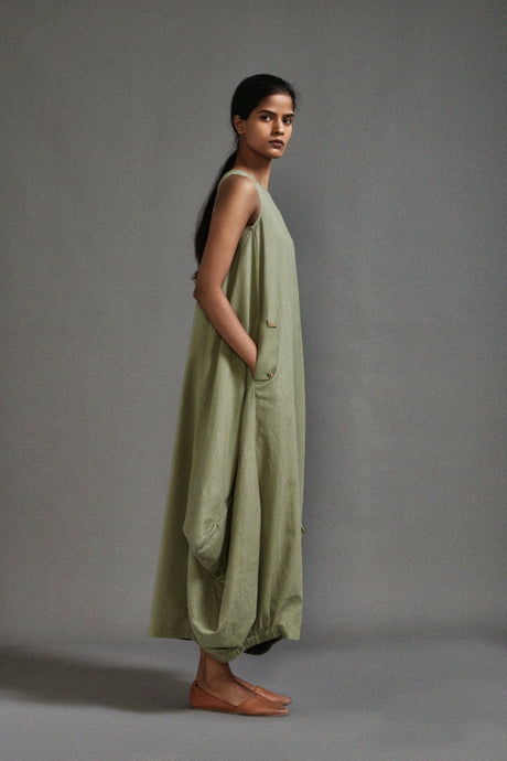 Side view of the sage Green New Vari Aakar dress showing the front pocket and draped hem