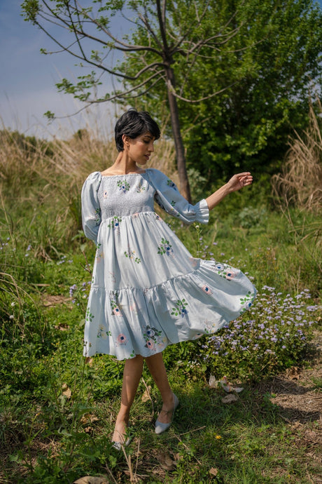 Model twirling in the Grey Smocking Dress with tiered skirt and ruffle cuffs, three-quarter view