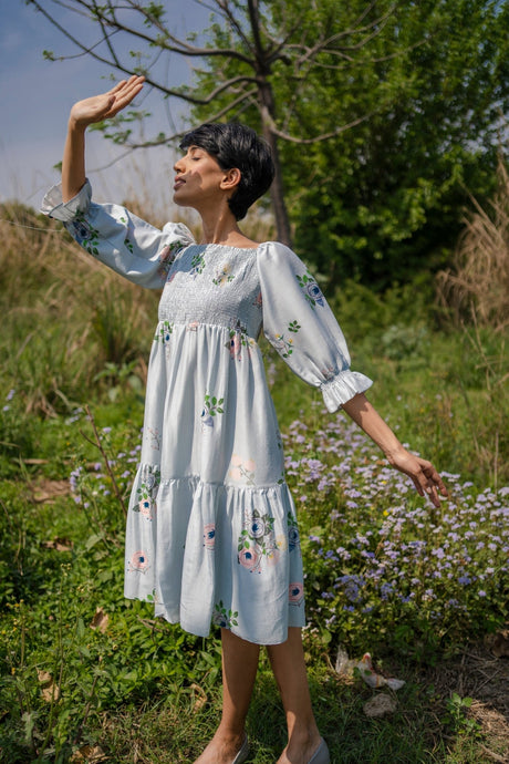 Model wearing the Grey Smocking Dress with arm raised, showing the ruffled sleeves, front view