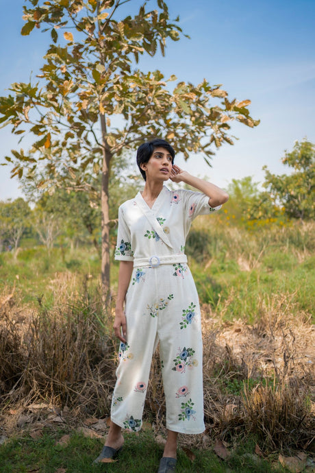 Model wearing the ivory floral jumpsuit with short sleeves, hand raised, front view