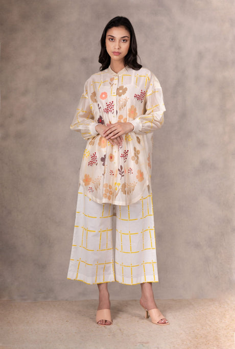 Model wearing the check pants and floral shirt, hands clasped, front view