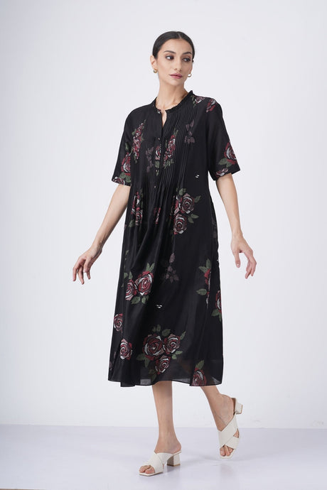Model walking in the black rose printed pleated dress with tie neck, three-quarter view